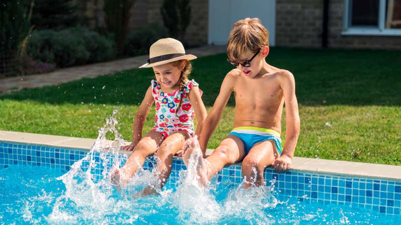 Niños jugando salpicando en la piscina